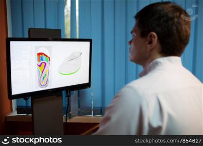 Orthopaedist at work with computer. He modeling orthopedic shoe using foot scan