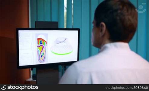 Orthopaedist working at the computer. He modeling orthopedic shoe using foot scan