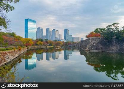 Osaka downtown skyline with lake or river and skyscraper buildings in Kansai in colorful Autumn season with red maple leaves, trees in park, urban city, Japan. Architecture landscape background.