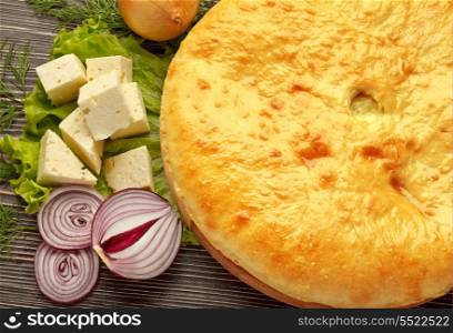 Ossetian cuisine. Kadyndzdzhin onion and cheese pie on wooden surface.