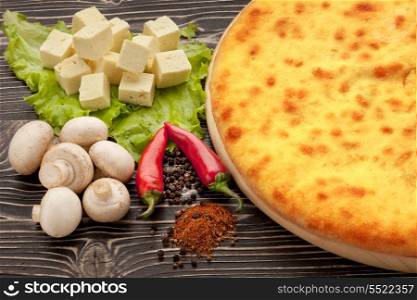Ossetian cuisine. Kozodjin meat pie and vegetables on wood.