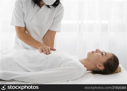 osteopathist treating female patient by massaging her body