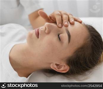 osteopathist treating female patient by massaging her face close up