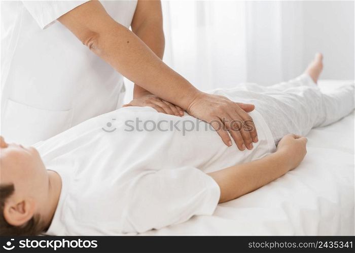 osteopathist treating kid by massaging his body