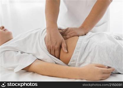 osteopathist treating kid by massaging his tummy