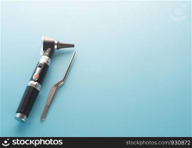 Otoscope with ear instrument on blue background.
