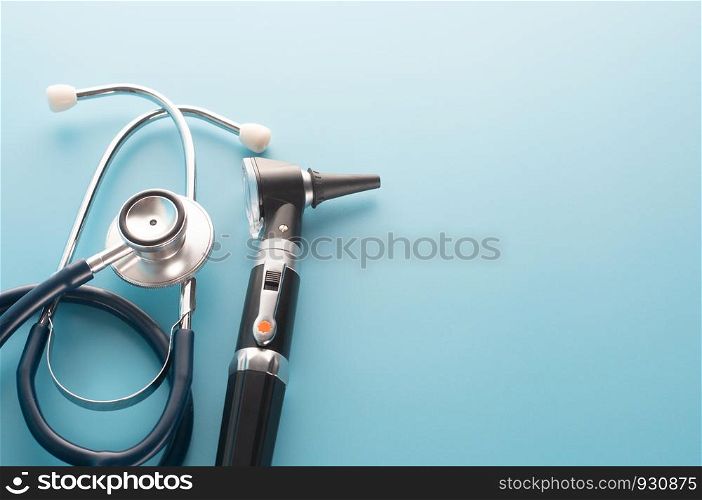 Otoscope with stethoscope on blue background.
