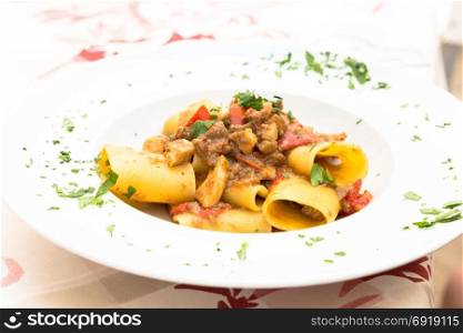 Otranto town, Puglia Region, South of Italy. Traditional Paccheri pasta with Swordfish, served with tomato, parsley, olive oil. Daylight, real restaurant in Otranto.