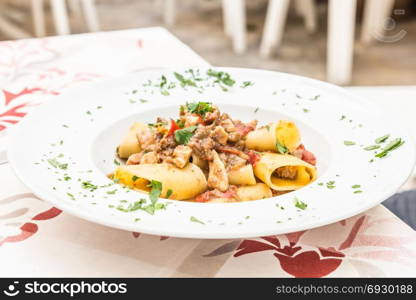 Otranto town, Puglia Region, South of Italy. Traditional Paccheri pasta with Swordfish, served with tomato, parsley, olive oil. Daylight, real restaurant in Otranto.