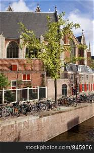 Oude Kerk and bikes along canal waterfront in Amsterdam, Holland, Netherlands.