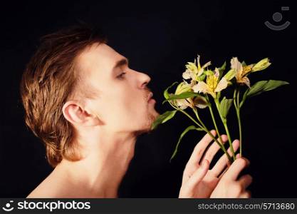 oung men sniffing bouquet of flowers on a black background