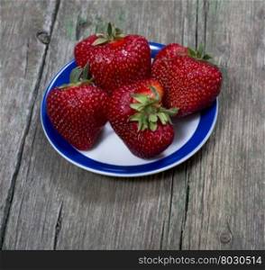 our big strawberries on a saucer, on a wooden table, a berry subject
