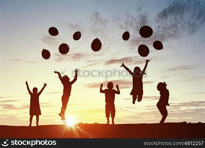 Our happy children. Silhouettes of group of children jumping on sunset background