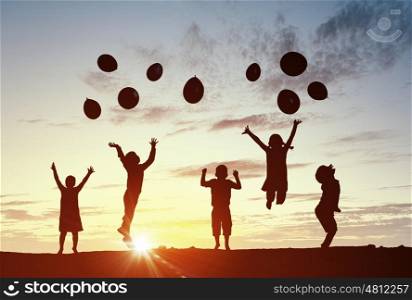 Our happy children. Silhouettes of group of children jumping on sunset background