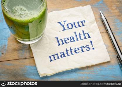 our health matters reminder or advice - handwriting on a napkin with a glass of fresh, green, vegetable juice
