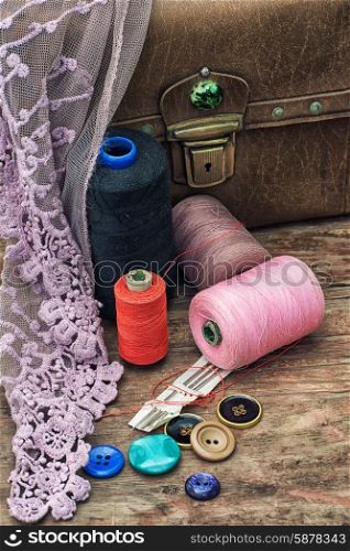 outdated tools tailor. spools of thread on background of old vintage suitcase with draped cloth with lace.Selective focus