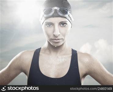 Outddor portrait od Young athletic swimer woman with googles and swimming cap, with sky on the back