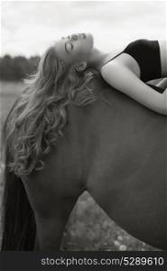 Outdoor art fashion photo of beautiful young lady with horse.