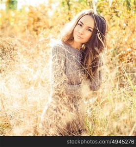 Outdoor atmospheric fashion photo of young beautiful lady. Autumn field. Autumn lanscape. Warm autumn. Warm spring