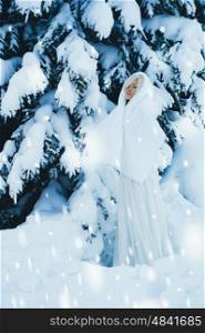 Outdoor atmospheric fashion photo of young beautiful lady in winter forest. Fur coat. Cold weather. Snowflakes