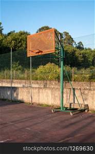 Outdoor basketball hoop with blue sky and trees at the background. City basketball court. Copy space