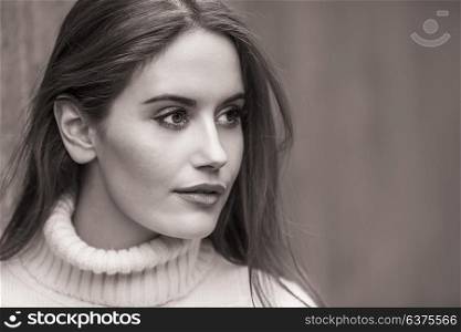 Outdoor black and white portrait of beautiful girl or young woman with wearing a white jumper