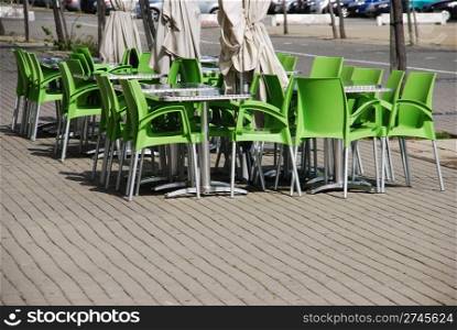 outdoor cafeteria with green plastic chairs, metallic tables and umbrellas