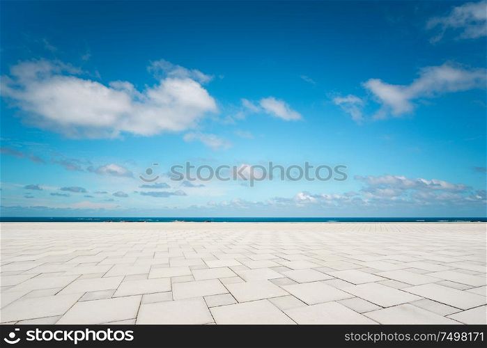 Outdoor empty square marble floor and sea under the blue sky .