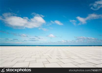 Outdoor empty square marble floor and sea under the blue sky .