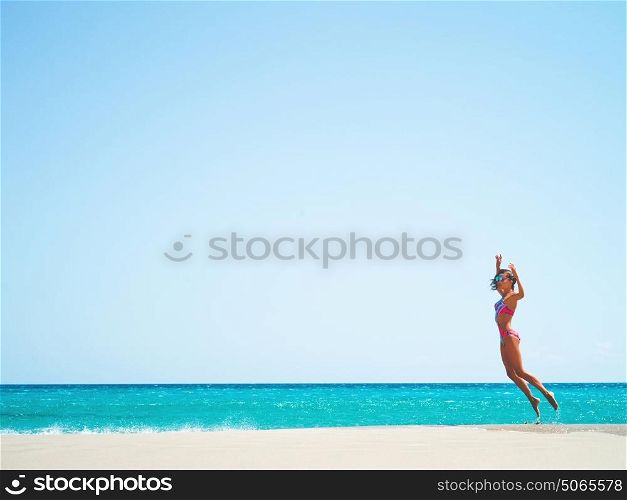 Outdoor fashion photo of beautiful happy slender woman jumping on sea. Beach travel. Summer vibes