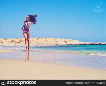 Outdoor fashion photo of beautiful happy slender woman running on sea. Beach travel. Summer vibes
