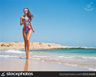 Outdoor fashion photo of beautiful happy slender woman running on sea. Beach travel. Summer vibes