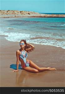 Outdoor fashion photo of beautiful happy slender woman sitting at sea. Beach travel. Summer vibes