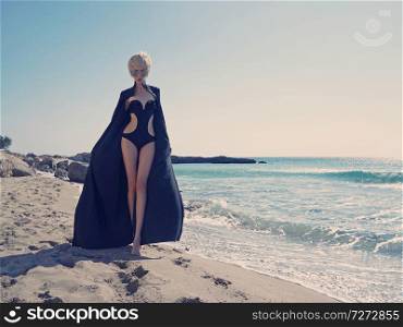 Outdoor fashion photo of beautiful slender woman in black tunic on the beach