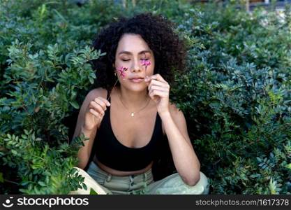 Outdoor fashion photo of beautiful young woman surrounded by flowers