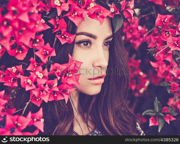 Outdoor fashion photo of beautiful young woman surrounded by flowers