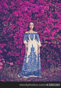 Outdoor fashion photo of beautiful young woman surrounded by flowers