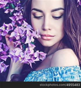 Outdoor fashion photo of beautiful young woman surrounded by flowers