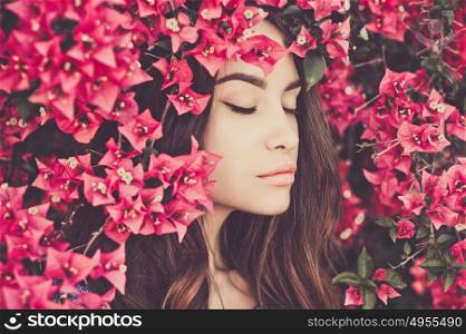 Outdoor fashion photo of beautiful young woman surrounded by flowers. Spring blossom