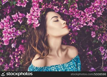 Outdoor fashion photo of beautiful young woman surrounded by flowers. Spring blossom
