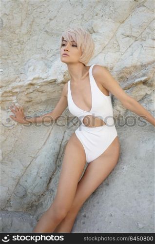 Outdoor fashion photo of graceful young woman in white swimwear on the beach. Fashion and beauty. Summer travel