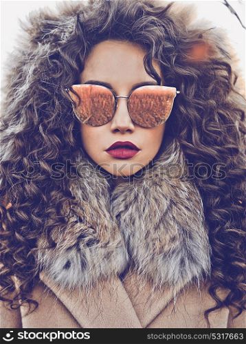 Outdoor fashion photo of young beautiful lady in autumn landscape. Beige coat, fur collar, sunglasses, wine lipstick. Fashion lookbook. Warm Autumn. Warm winter
