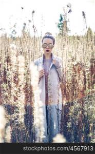 Outdoor fashion photo of young beautiful lady in autumn landscape with dry flowers