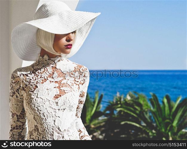 Outdoor fashion photo of young beautiful lady in white hat at sea. Summer Beach travel. Summer vibes