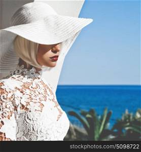 Outdoor fashion photo of young beautiful lady in white hat at the sea. Summer Beach travel. Summer vibes