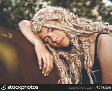 Outdoor fashion portrait of beautiful young girl with brown horse. Hippie style. Summer vibes. Autumn season