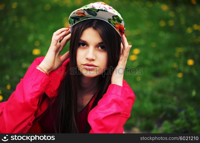 Outdoor fashion portrait of stylish girl. Young brunette woman posing, wearing swag floral cap. Lifestyle portrait bright toned colors.