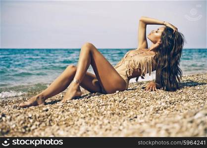 Outdoor fashion portrait of tanned lady in sexual swimsuit posing at beach