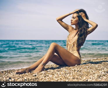 Outdoor fashion portrait of tanned lady in sexual swimsuit posing at beach