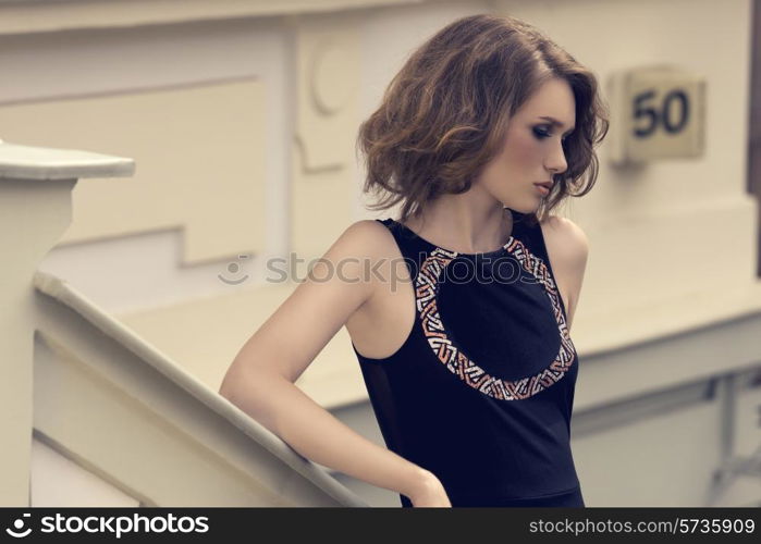outdoor fashion shoot of sensual young female with stylish black dress and natural hair-style